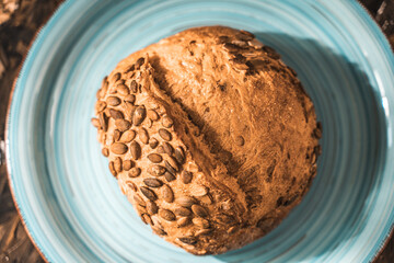 A loaf of rye bread on a turquoise or blue plate on a brown background. Close-up. Top view, Space for text