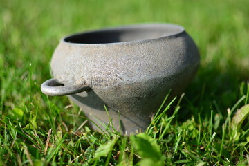 Old soviet style pot with two handles used on furnace. Vintage iron metal dish on green grass.