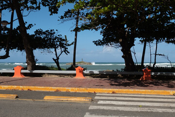 Coastal road view framed by trees overlooking Neptune Island and the ocean, Puerto Plata, Dominican...