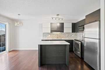 A kitchen with a stainless steel refrigerator and a black island