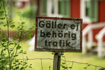 Obraz premium weathered swedish traffic sign on wooden post in rural area.