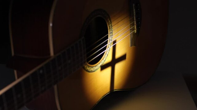 Acoustic guitar with cross shadow illuminated by light