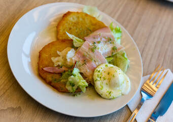 Plate of tasty potato pancakes with bacon, egg and greens
