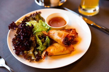 Asian cuisine. Delicious Thai deep-fried shrimp spring rolls traditionally serving with sweet chili sauce and fresh lettuce..