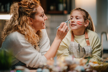 Mother painting daughter's face for easter celebration at home