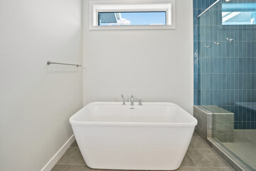 A white bathtub sits in a bathroom with a blue tile wall