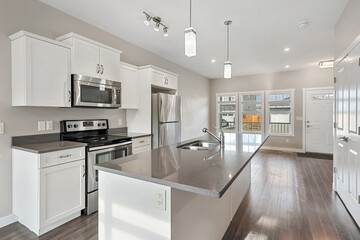 A kitchen with a large island and a stainless steel refrigerator