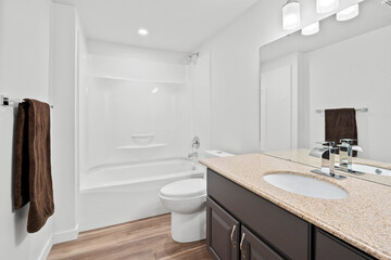 A bathroom with a white toilet and a brown towel hanging on the wall