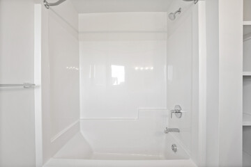 A white bathroom with a white tub and a white shower