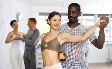 Portrait of smiling young woman and adult African American man practicing in modern choreography...
