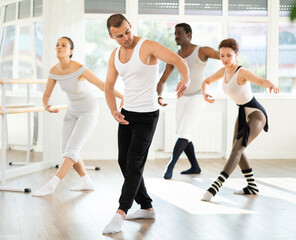 Obraz premium Group of men and women of different nationalities rehearsing ballet movements in the studio