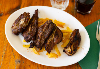 Spanish dish of pork cheeks with french fries presented on wooden table