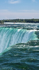 Niagara Falls. A pleasure boat with people near the huge famous waterfall. View from the Canadian side. Nature scenery. Photo for advertising