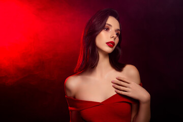 Tempting brunette woman in red dress with glamorous makeup against red and black background