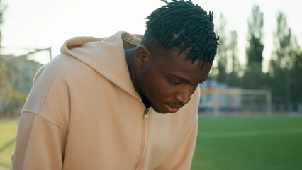 African American sport man heavy breathing sweating stop morning workout on city stadium outdoors...