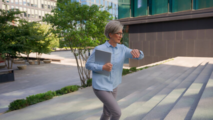 Old Caucasian businesswoman mature woman professional business lady walking up stairs in city...