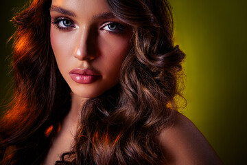Naklejka premium Elegant portrait of young brunette woman with glamorous makeup and voluminous hairstyle on dark green background