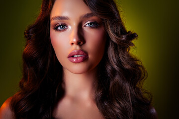 Fototapeta premium Close-up portrait of a glamorous young woman with elegant hairstyle and vibrant makeup on a dark green background