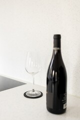 classic wine glass stands next to a bottle of expensive wine. Modern kitchen with white stone countertop. Minimalism style