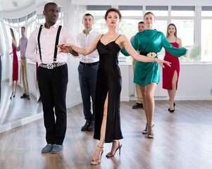 Fototapeta premium Positive men and women of different ages posing in pairs in dance studio