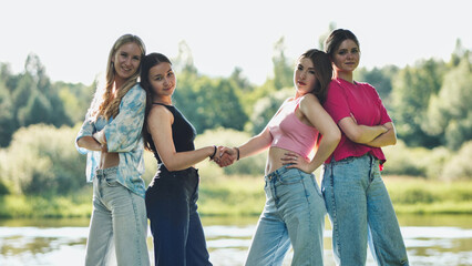 Teenage friends greeting, smiling beside river, bonding during outdoor meetup with positive camaraderie
