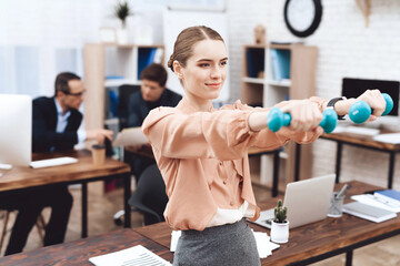 A girl is doing gymnastic exercises at work. She works in a business office. She is tired.