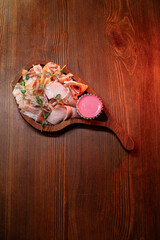 Beautiful slicing of fat and delicious fresh bacon on a wooden plate of unusual shape in the restaurant.