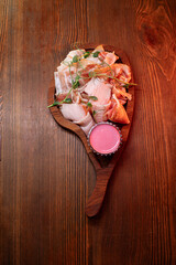 Beautiful slicing of fat and delicious fresh bacon on a wooden plate of unusual shape in the restaurant.