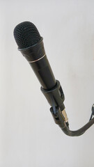 black wired microphone on a white wall background.