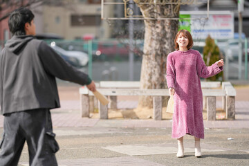 A Japanese man and woman in their 20s are playing hagoita, a traditional New Year's game, in a deserted park in Sakae, Naka Ward, Nagoya City, Aichi Prefecture.