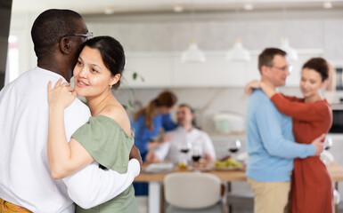 Multiethnic male and female couples slow dancing in kitchen