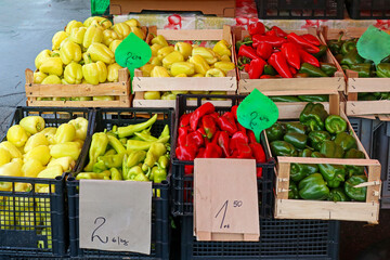 Fresh organic raw colorful peppers in crates sold on market stall outside