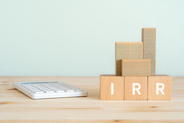 IRRと書かれたブロック、電卓、不動産の模型