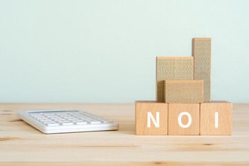 NOIと書かれたブロック、電卓、不動産の模型