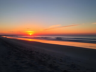 Serene Beach Sunrise:  A mesmerizing sunrise paints the sky with vibrant hues of orange, pink, and purple, casting a warm glow on the tranquil beach, inviting calm and reflection. 