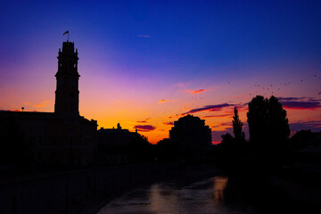 Silhouettes of historical buildings against a sunset sky at twilight time in Oradea, Romania
