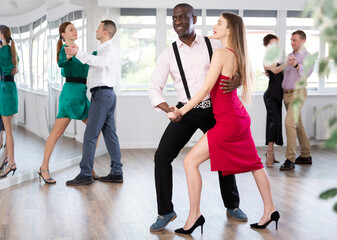 With unhurried music, woman with African man in couple spins to rhythm of waltz during lesson for...