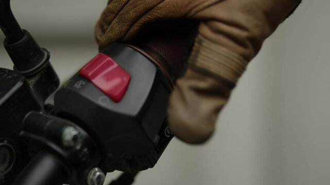 The biker takes the steering wheel of the motorcycle with his right hand, he starts the motorcycle twice using the kill switch and the motorcycle starter button