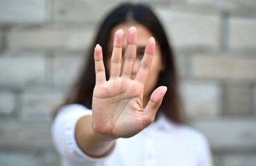 Latina woman makes stop gesture. Serious emotion displayed. Protest against violence. Campaign for equality, respect. Photo conveys message of no violence against women. Anti-discrimination movement.