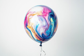 Colorful balloon with marbleized paint effect floats against white background