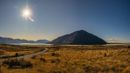 Driving the winding road through arid tussock covered terrain to isolated Lake Ohau