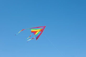 One colorful kite flying in blue sky