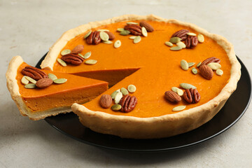 Tasty homemade pumpkin pie with seeds and nuts on grey table, closeup
