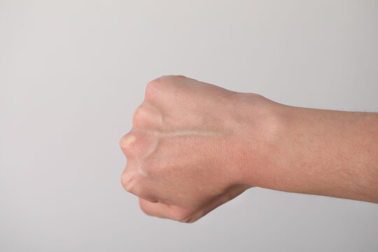 Woman with visible hand veins on light grey background, closeup