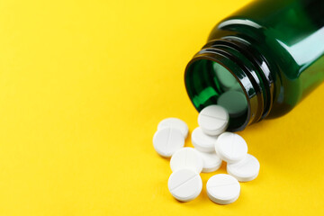 Medical bottle with antibiotic pills on yellow background, closeup. Space for text