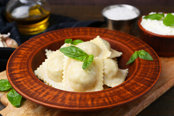 Delicious ravioli with cheese and basil served on wooden table, closeup