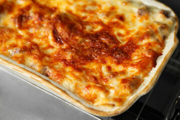 Baking dish with delicious cooked lasagna in oven, closeup