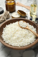 Soy wax and other supplies for making candles on white marble table, closeup