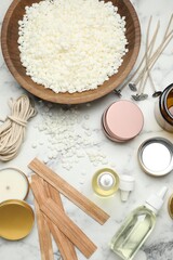 Soy wax and other supplies for making candles on white marble table, flat lay