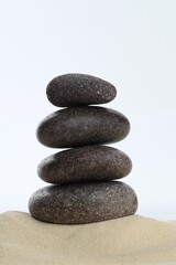 Stack of rocks on sand against white background. Harmony and life balance